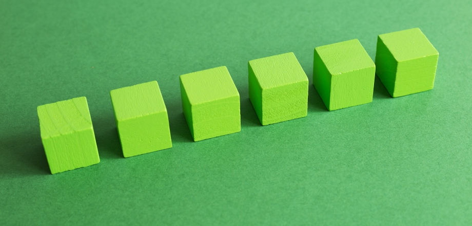 Green cubes in a row across a darker green background without any deviation represents predictability.