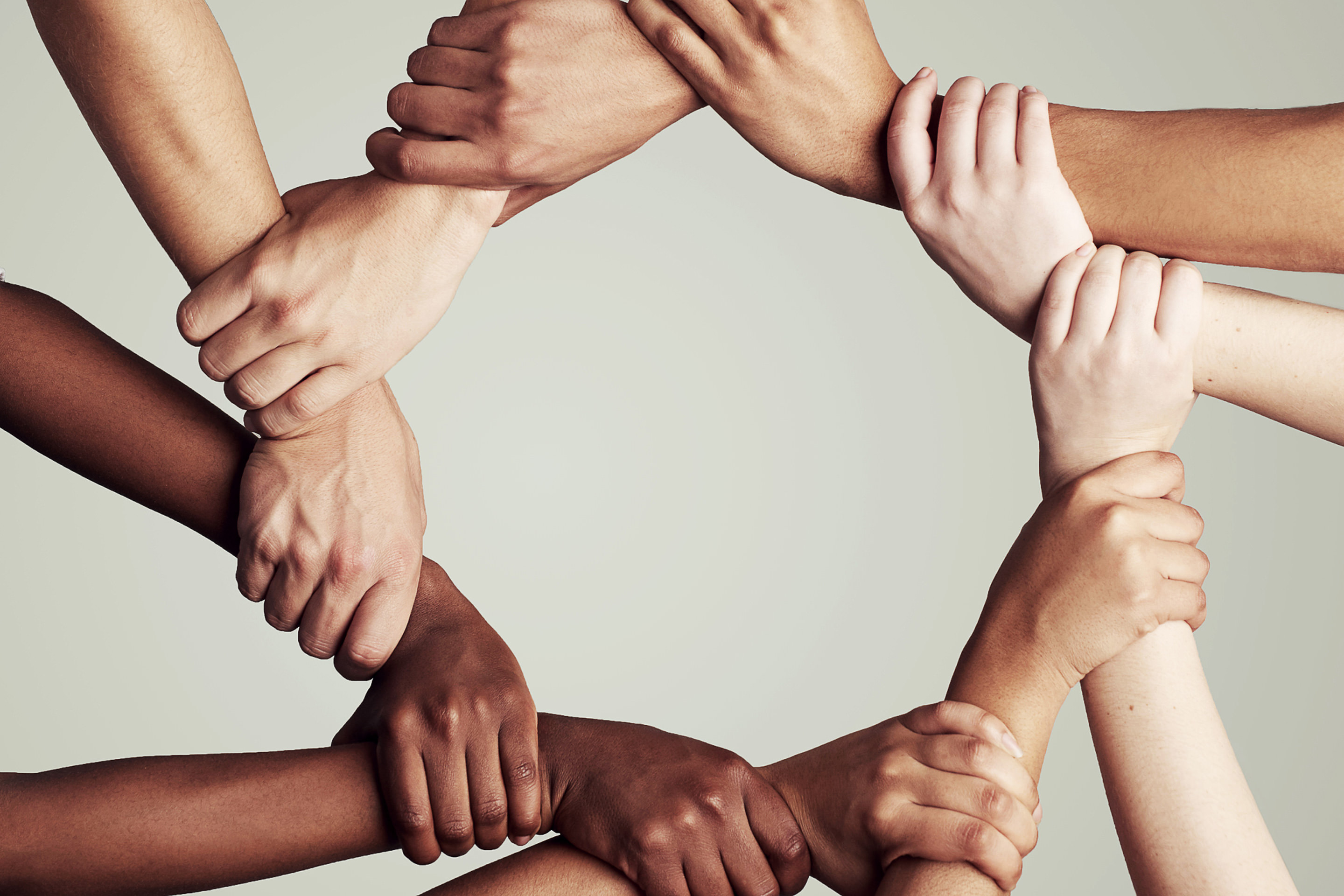 Cropped shot of a diverse group of people holding hands in a circle.