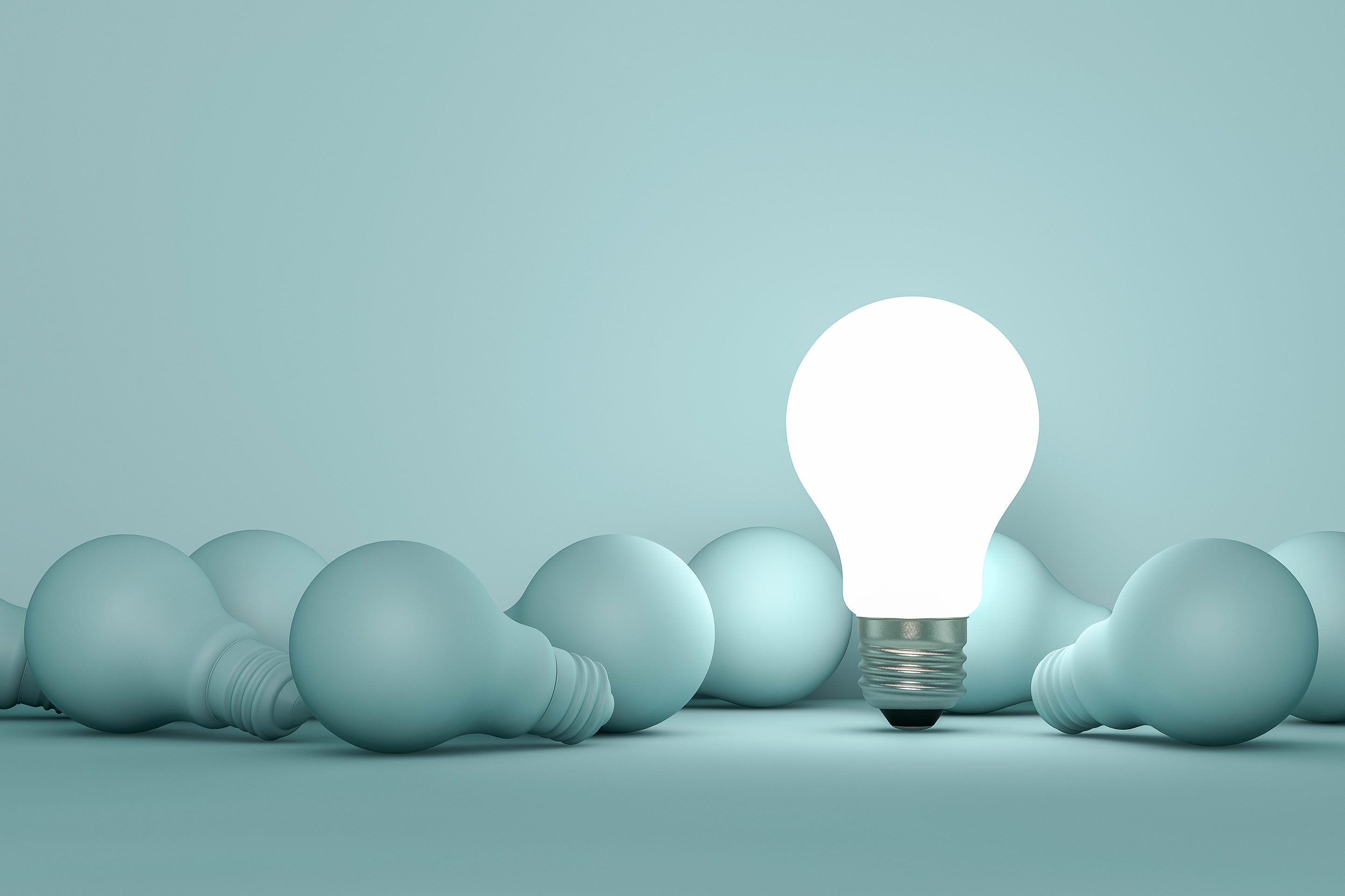 A bright lightbulb stands among a group of dark lightbulbs representing intelligence