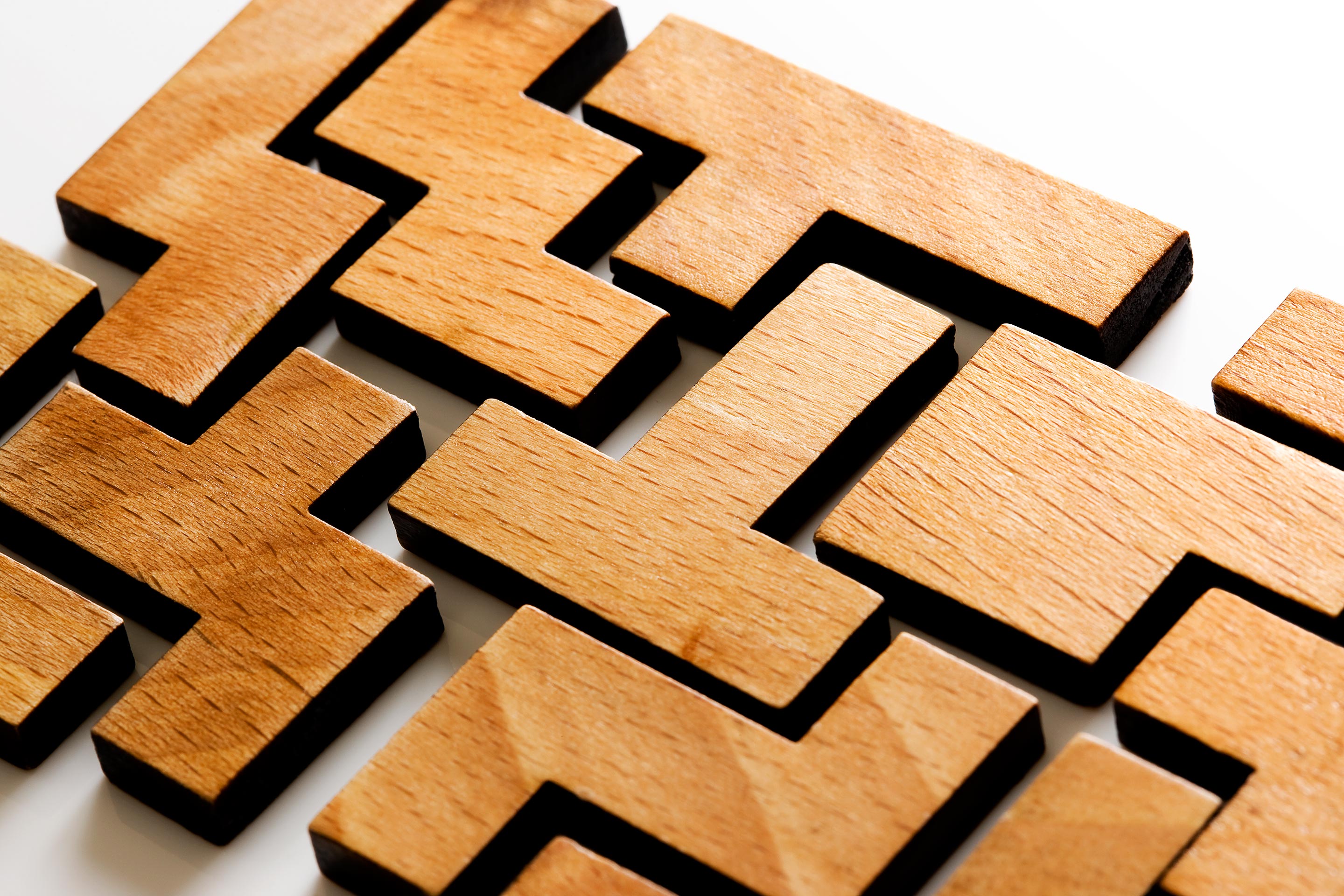 Wooden blocks are all different shapes yet come together to connect and create a solid piece.