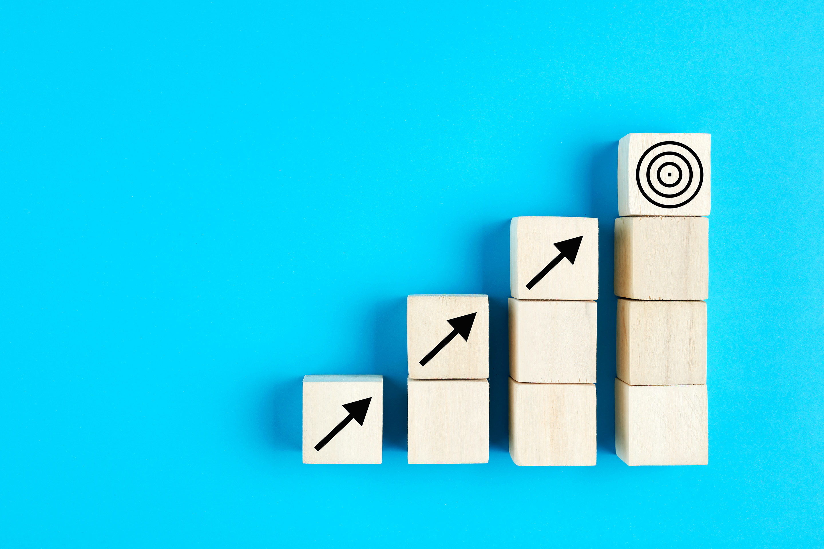 Four ascending wooden blocks on a blue background as a metaphor for potential investment returns
