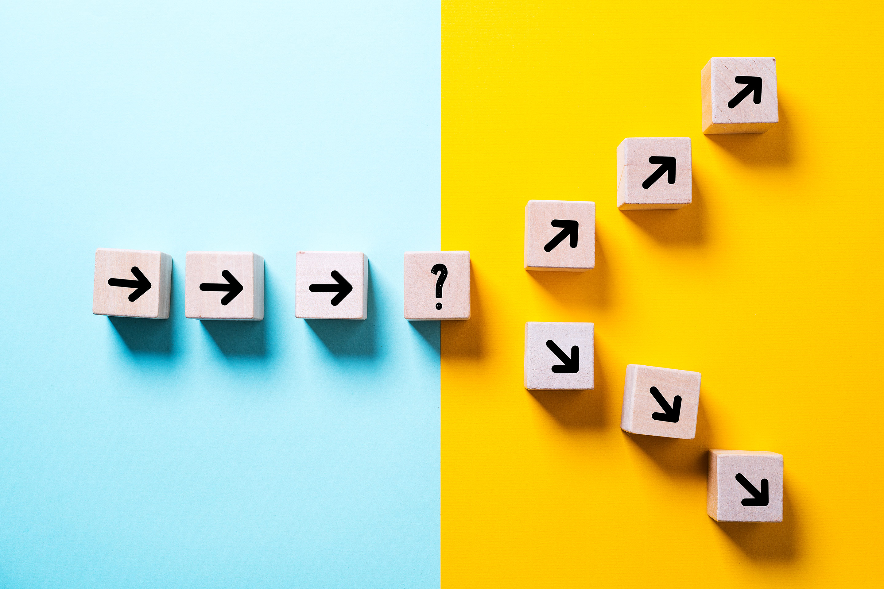 A series of wood blocks with arrows coming to a crossroads, representative of making financial decisions