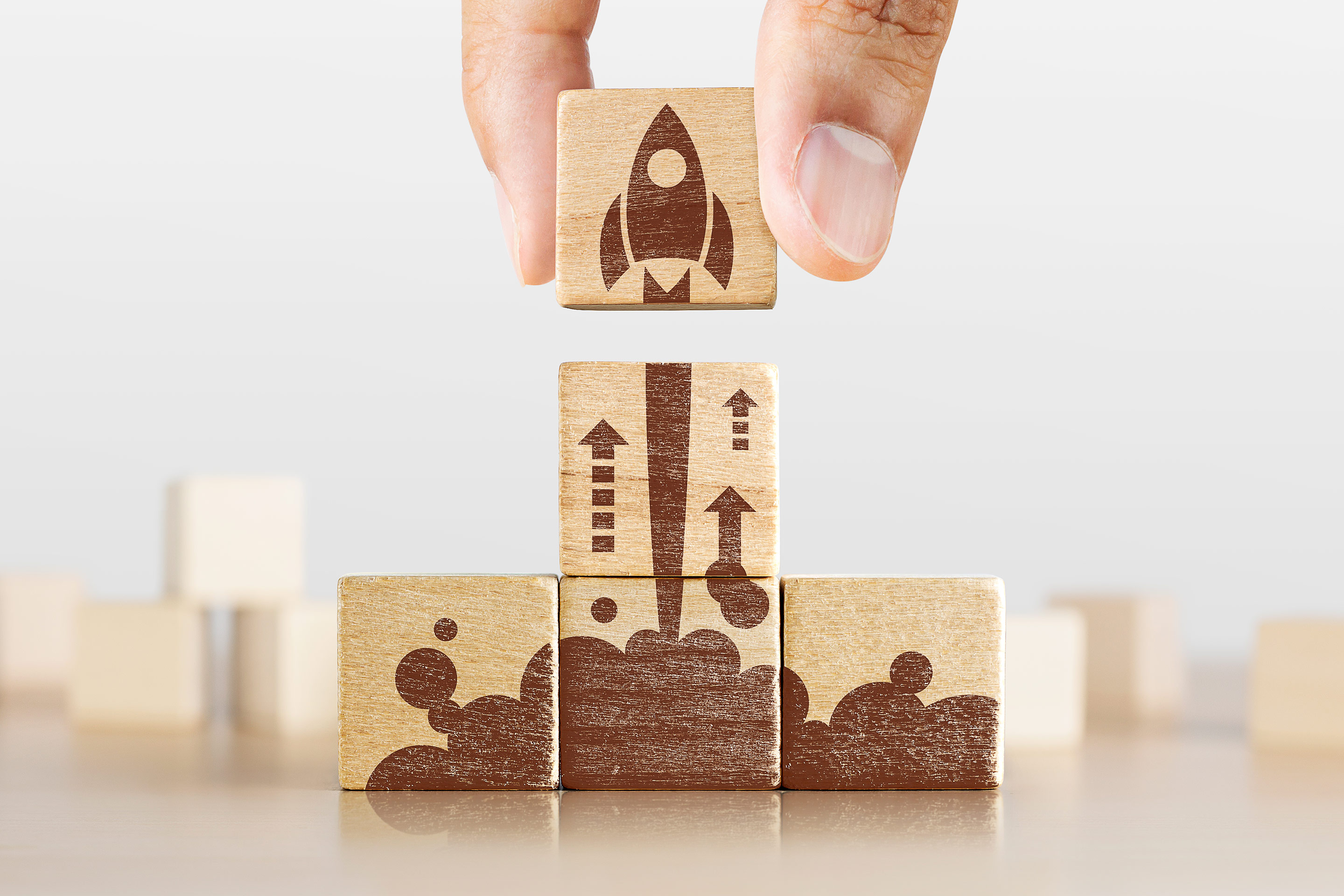 Image of a hand completing a wooden rocket ship puzzle, representing progress and modernization