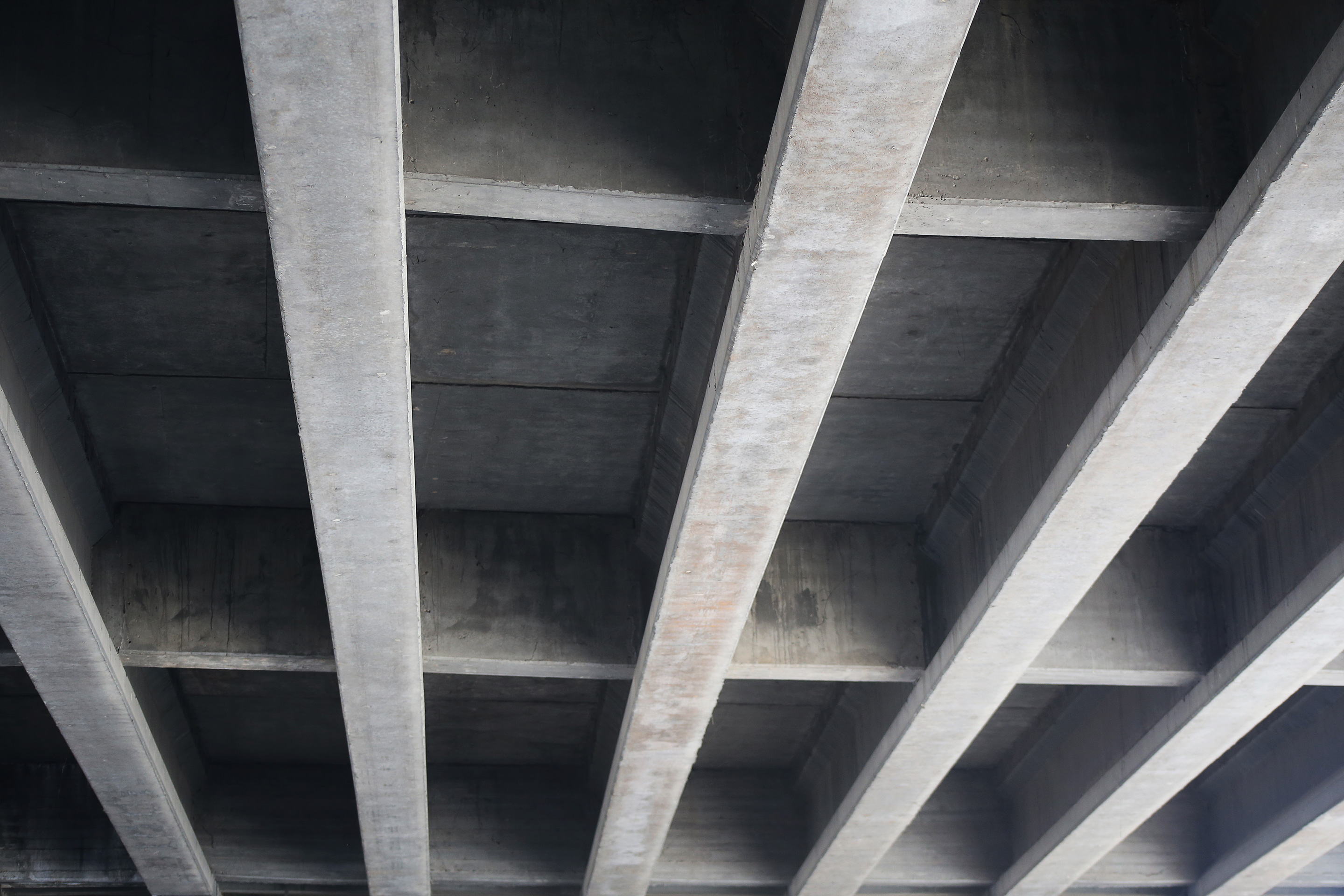 An industrial concrete ceiling with strong, straight support beams.