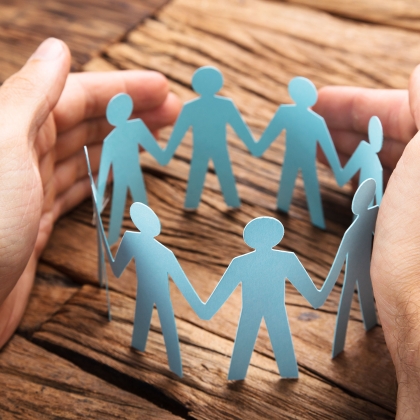 Hands surround a circular cutout of people holding hands, representing communities.