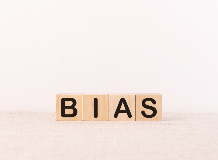 Wooden blocks spell out the word bias against a pale monochromatic background