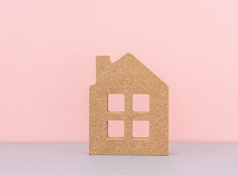 A wooden house on a pink and purple background representing community.