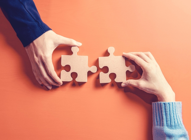 Two different individuals hold puzzle pieces that will interlock to create connectivity
