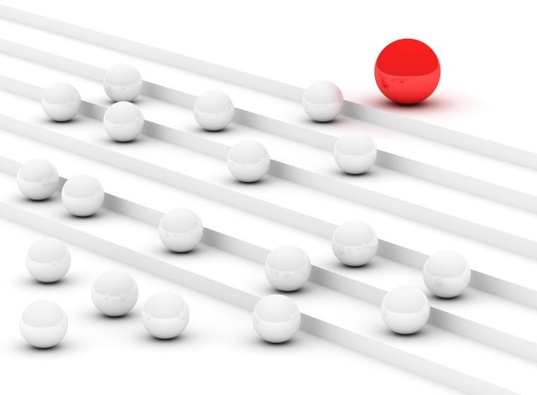 Standing out boldly against a white background, a large red ball towers over a dozen or so smaller gray and white balls. All the balls are thoughtfully placed on a set of white steps.