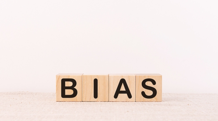 Wooden blocks spell out the word bias against a pale monochromatic background