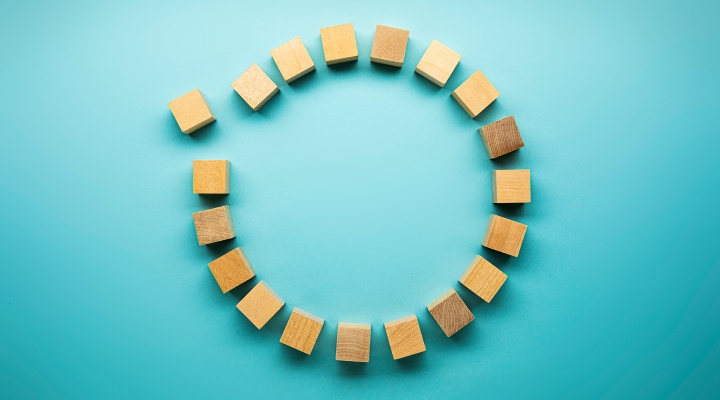One block separates from a circle of wooden blocks on a blue background representing communities
