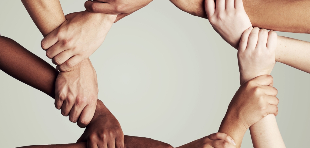 Cropped shot of a diverse group of people holding hands in a circle.