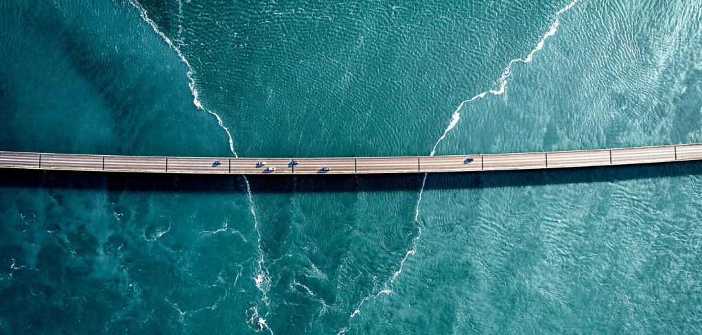 Surprising photo of a bridge dotted with cars, seen from high above over striking green water