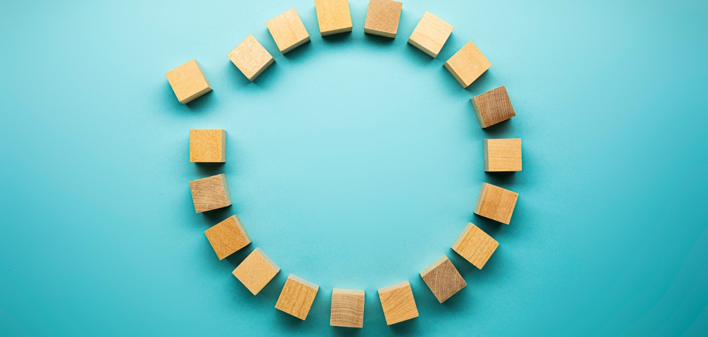 Wooden blocks in a connected circle against an aqua background, representing community