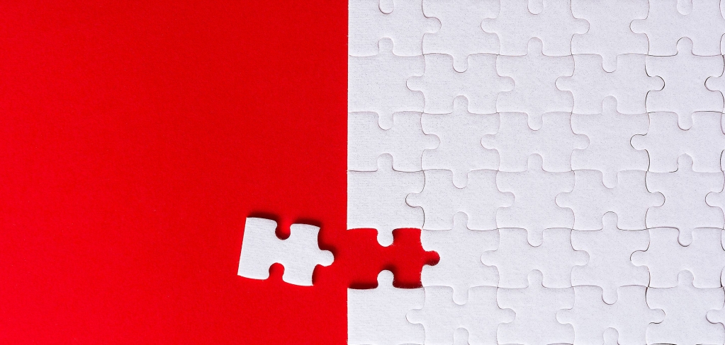 A single red puzzle piece overlaps a field of white pieces, representing adaptability.