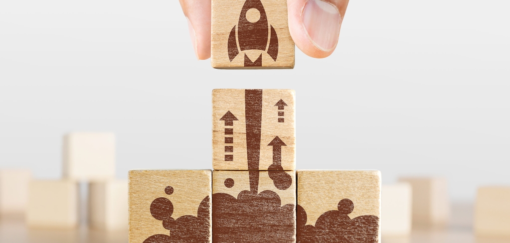 Image of a hand completing a wooden rocket ship puzzle, representing progress and modernization