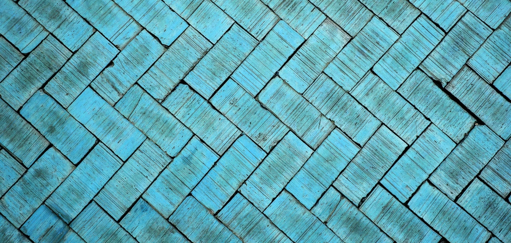 Bright turquoise bricks, with unique markings caused by age, are laid in an eye-catching chevron pattern across the entire photo.