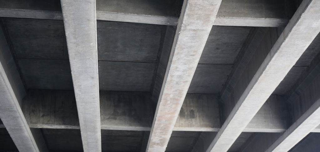 An industrial concrete ceiling with strong, straight support beams.