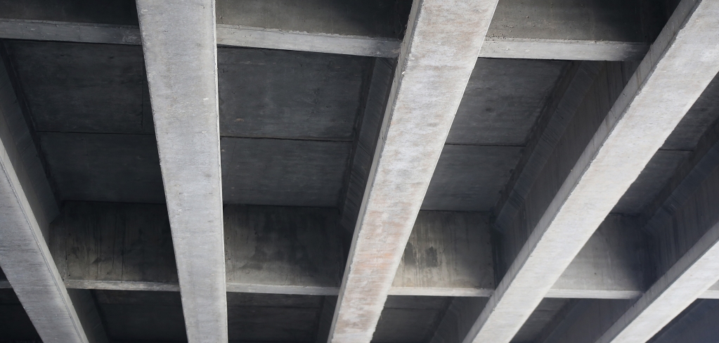 An industrial concrete ceiling with strong, straight support beams.