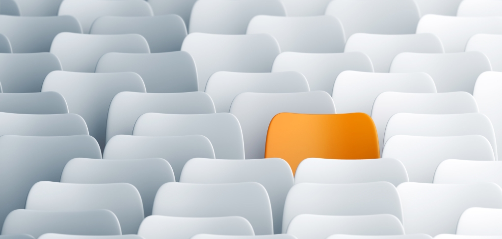 A single orange chair in a group of stark white chairs is certainly unpredictable.