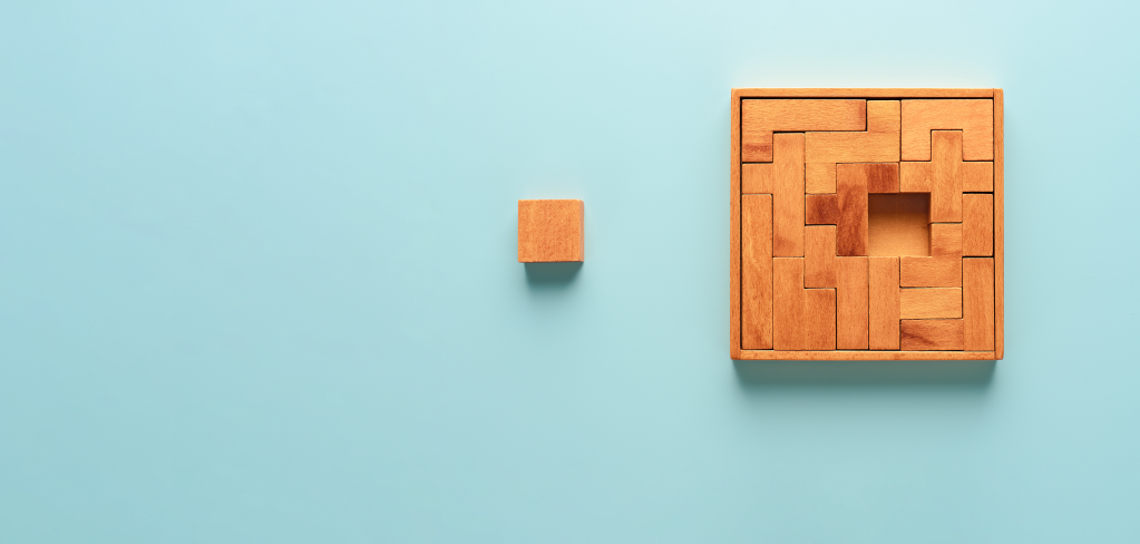 Wooden puzzle with one, central piece pulled out on a light blue background