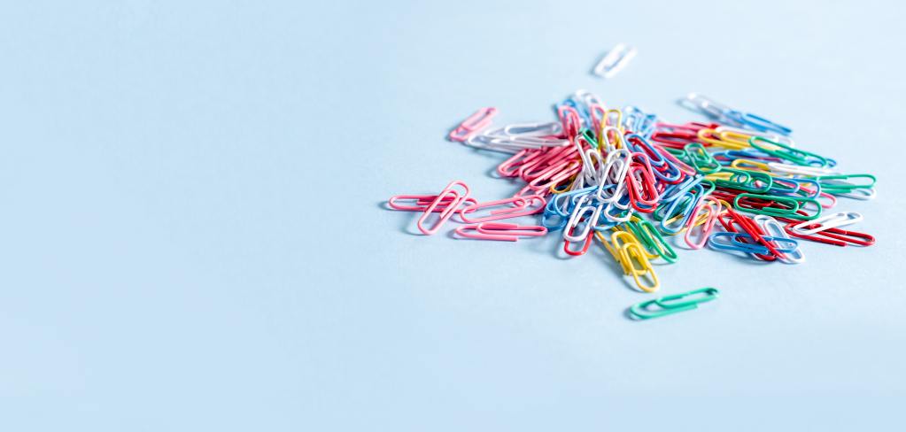 A pile of colorful paperclips on a light blue background