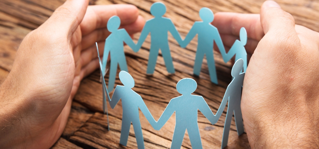 Hands surround a circular cutout of people holding hands, representing communities.