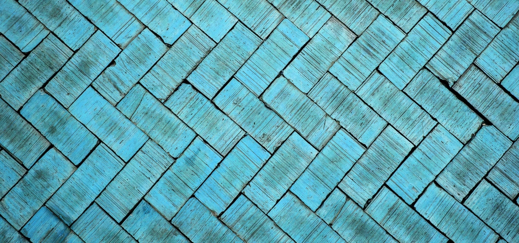 Bright turquoise bricks, with unique markings caused by age, are laid in an eye-catching chevron pattern across the entire photo.