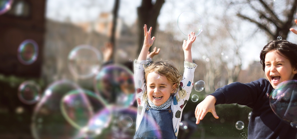Small children having fun playing with bubbles, a reminder of what's most important about investing.