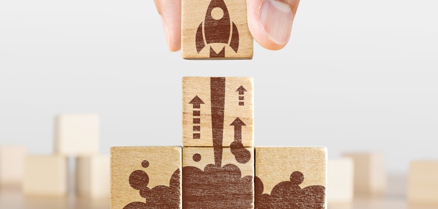 Image of a hand completing a wooden rocket ship puzzle, representing progress and modernization