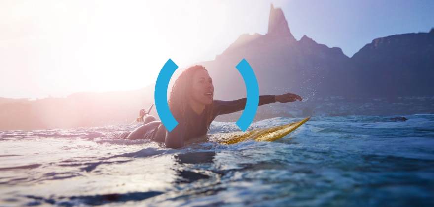 Independence and ease. A woman paddles through the water on a surfboard in a scenic location.