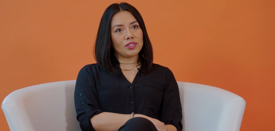 Armonia Garcia Diaz sits in a white chair with an orange background