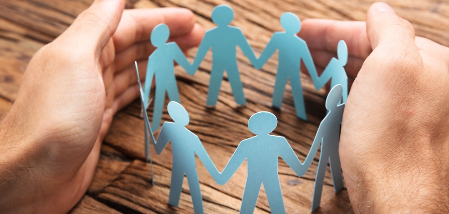 Hands surround a circular cutout of people holding hands, representing communities.