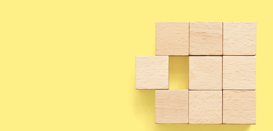 Six natural wood blocks forming a symmetrical square, with one block sliding in or out of alignment