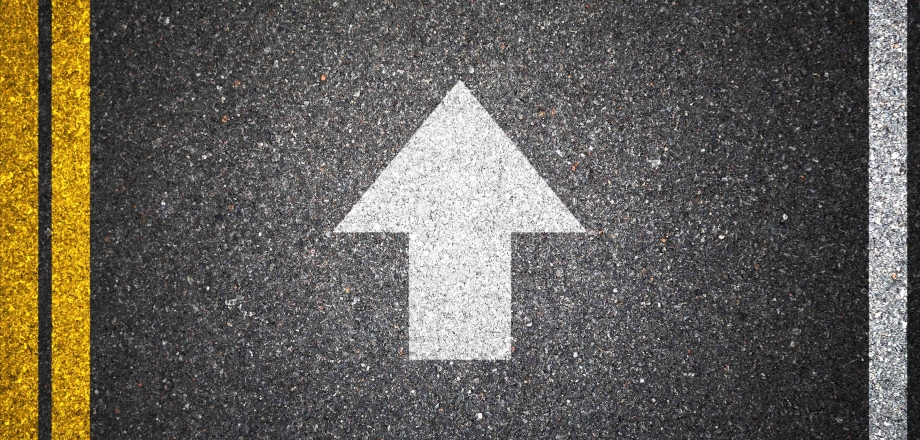 An image of a white arrow forward on a road as a metaphor for considering investment goals