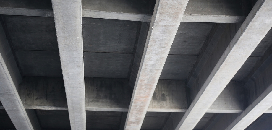 	An industrial concrete ceiling with strong, straight support beams.