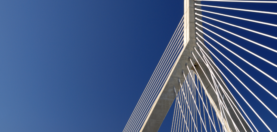 A striking upward support of a suspension bridge high against a bold blue sky, suggesting movement into the future.