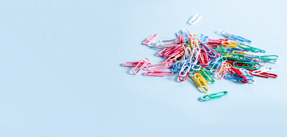 A pile of colorful paperclips on a light blue background