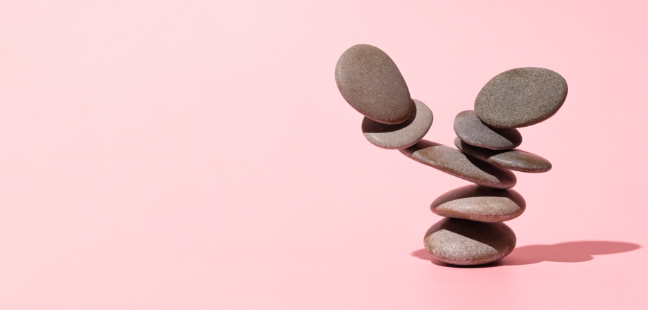 Stones balanced on top of one another against a pink background