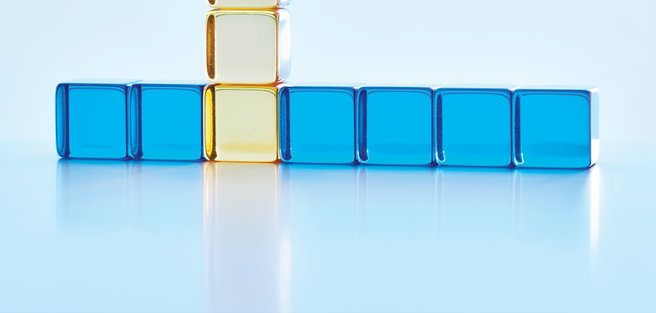 A row of bright blue glass squares are intersected by a vertical line of clear gold squares, representing a rising trend.