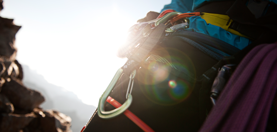 A close-up photo zeroes in on the safety gear on the hip of a mountain climber.