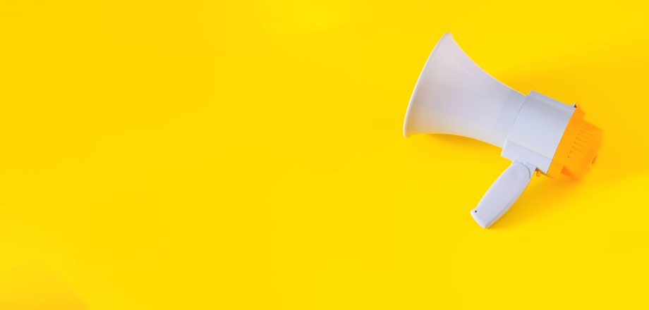 White megaphone lying on a yellow background