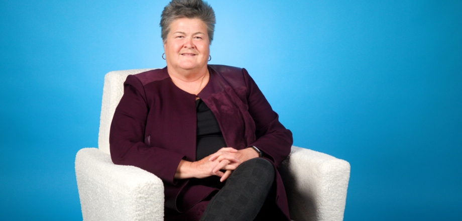 Rhonda Cook sits in a white chair with a blue background